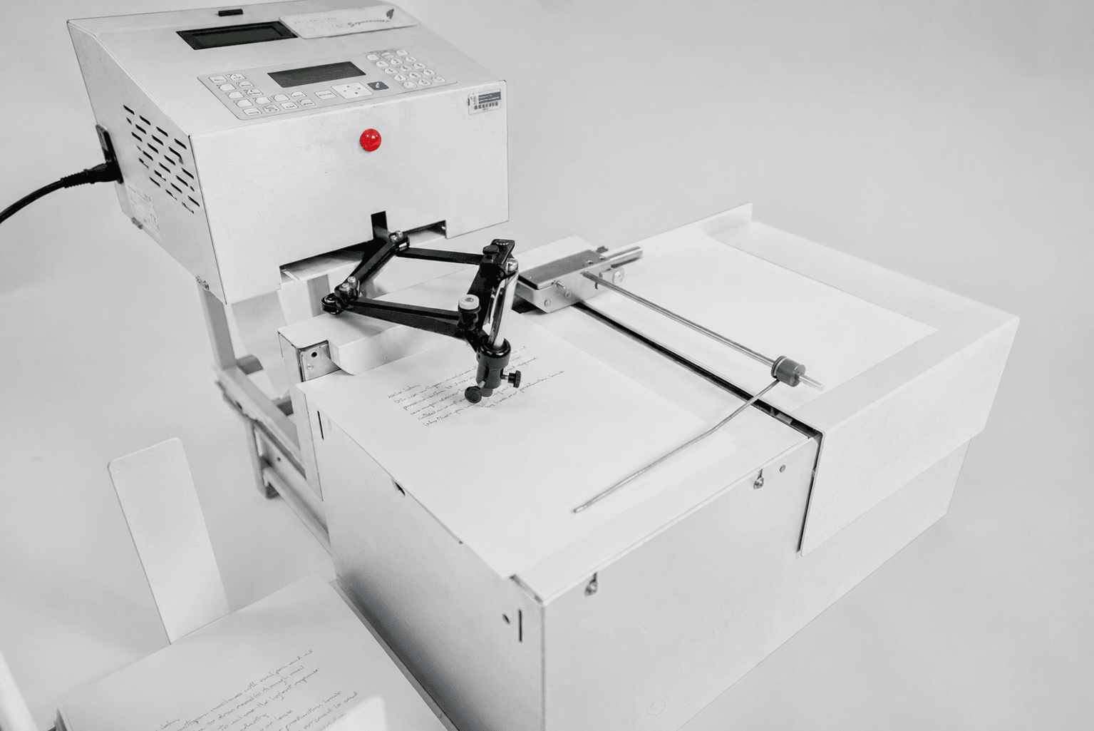 Close-up of a Universal Plus autopen machine writing a letter with a real pen